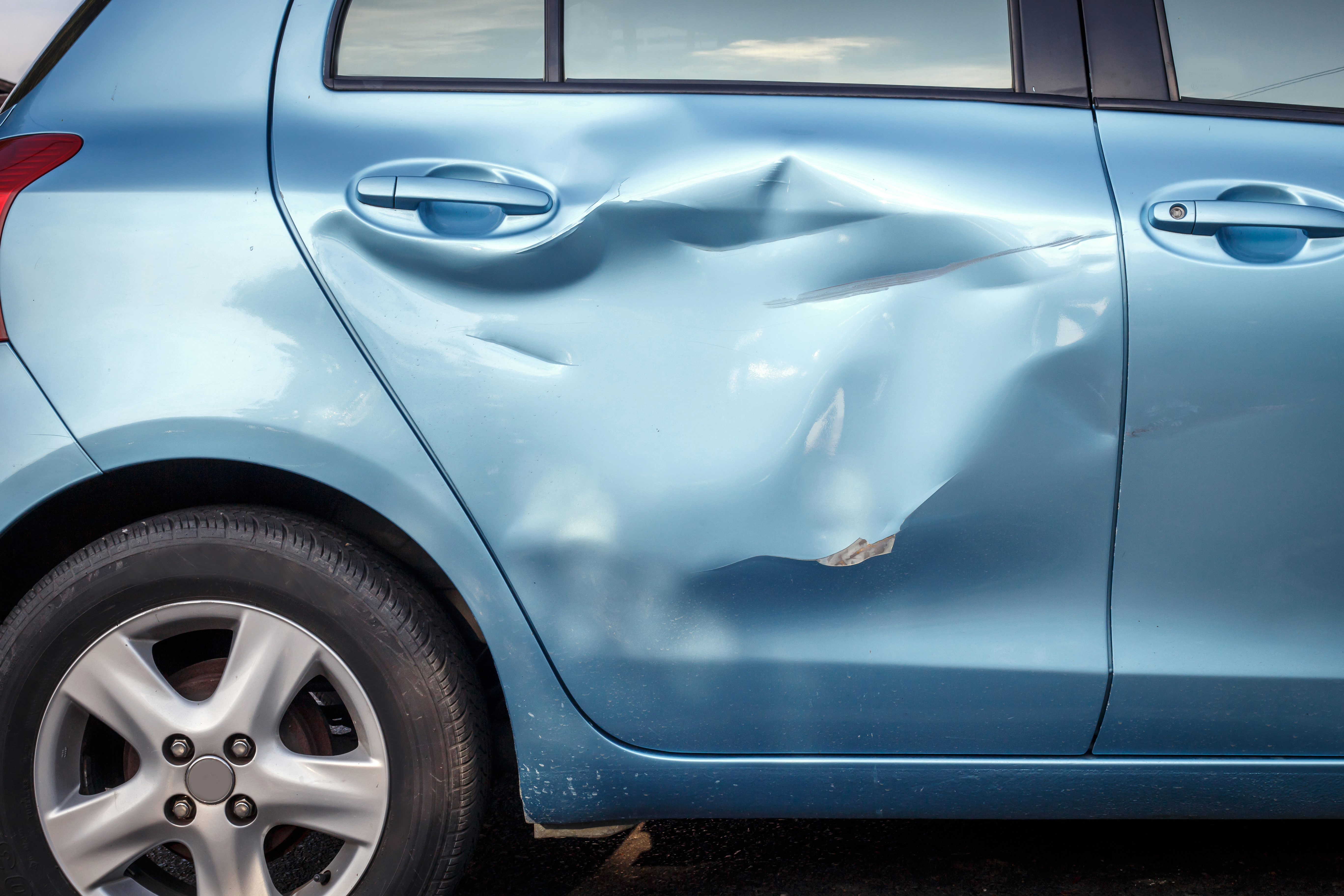 side view of a blue car with accident damage across the right side